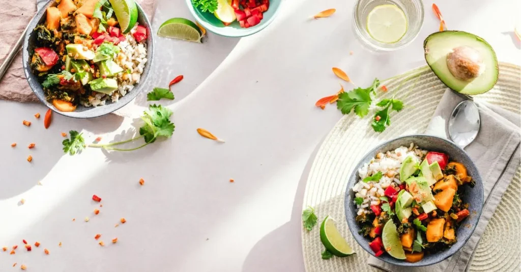 A flat lay of a healthy meal with colorful vegetables, grains, and a glass of water.